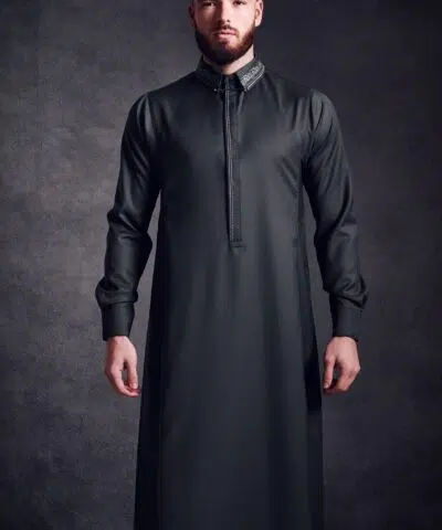 Homme debout portant un fantastique QAMIS AL AMEER AA224 gris foncé.