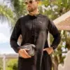Homme aux cheveux châtains portant des lunettes de soleil et un sac à main noir vêtu d'un fantastique qamis al ameer aar2408 noir.