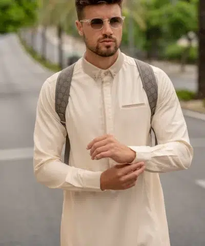 Homme portant des lunettes de soleil, un sac à dos et un sublime qamis al ameer aar2422 crème.