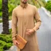 Homme aux cheveux chatains avec des lunettes de soleil et une petite barbe portant une magnifique qamis al ameer aar2425 marron clair avec une sacoche marron.